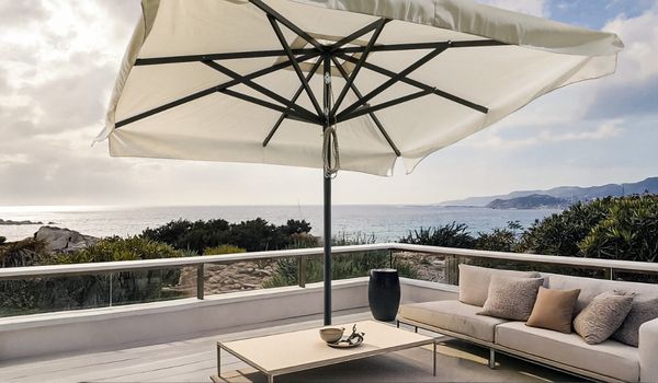 ombrellone a palo centrale con telo bianco su terrazzo